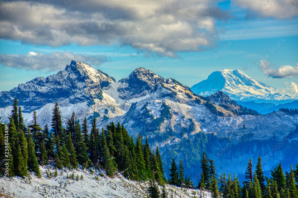 Fototapeta premium Sunset falls on two of the peaks of the Tatoosh Mountain Range (left) inside Mt. Rainier National Park. Mt. Adams, a dormant volcano, can be seen in distance (right). 