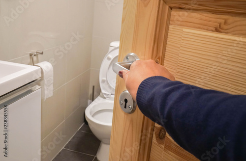 close up woman hand with dark blue sweater open the toilet door handle