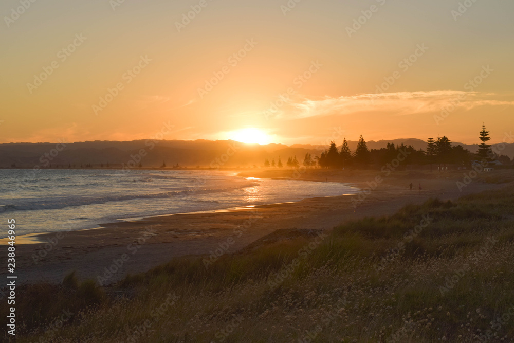 The bright sun sets on a quiet beach in Gisborne, New Zealand. The bright sun sets on a quiet beach in Gisborne, New Zealand.