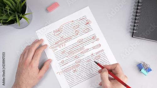 Teacher correcting an exam or homework with a red marker pointing out all the errors in the text. photo