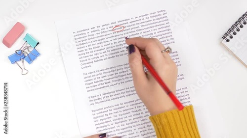 Teacher correcting an exam or homework with a red marker pointing out all the errors in the text. photo