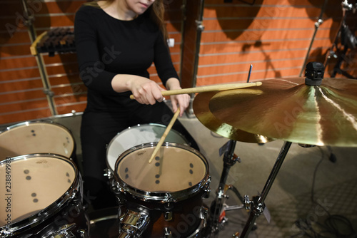 Professional drum set closeup. Beautiful young woman drummer with drumsticks playing drums and cymbals, on the live music rock concert or in recording studio 
