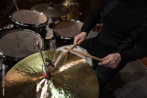 Professional drum set closeup. Man drummer with drumsticks playing drums and cymbals, on the live music rock concert or in recording studio 