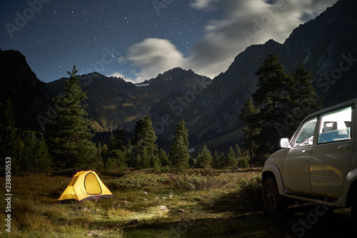 Camping with a car, yellow tent at night with moonlight at mountain area