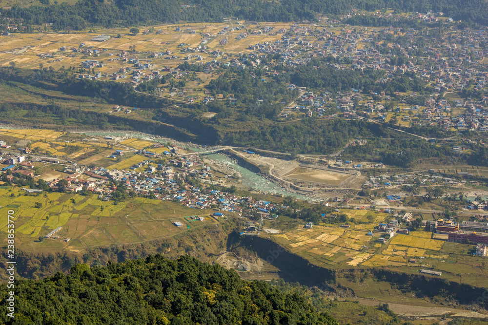 Village in a green mountain valley with river and fields. air photography
