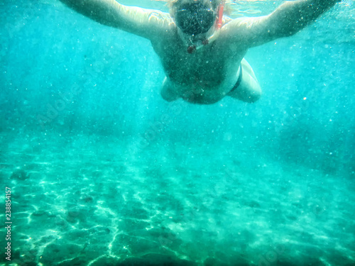 Man swimming under water into the sea