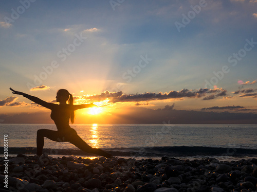 Fototapeta Naklejka Na Ścianę i Meble -  Young healthy woman practicing yoga fitness exercise on the beach at sunset. Healthy lifestyle concept. Copy space text