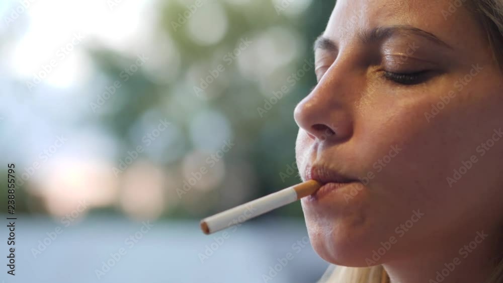 Slow motion profile close-up of a woman lighting a cigarette and smoking