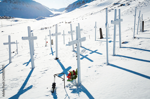 Longyearbyen, Norway in April. Old cemetery white crosses in snowy sunny weather. Blue sky, mountains in snow. Spitsbergen, Northern Norway in spring.