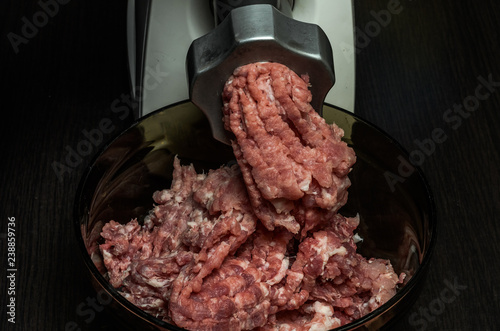 The cook grinds meat in minced meat on an electric meat grinder