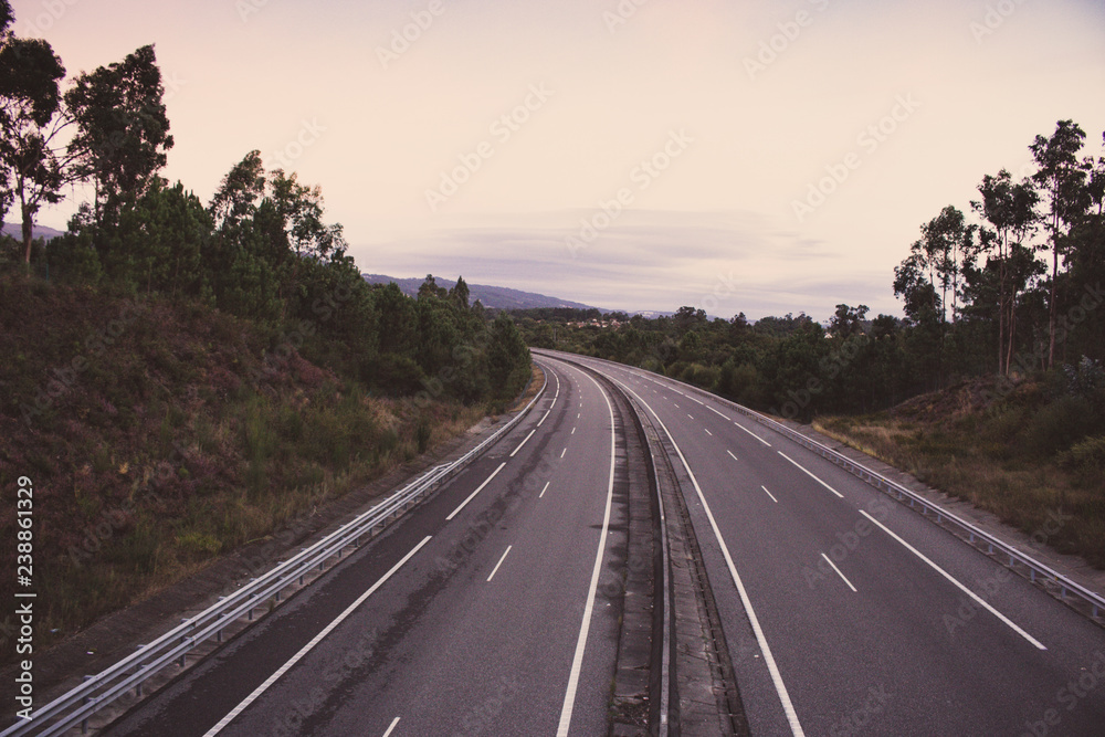 Wide empty highway with curve in the morning. Travel and destination background. Free asphalt road with mountain background. Motion and speed concept. Trip and journey concept. Driving concept.