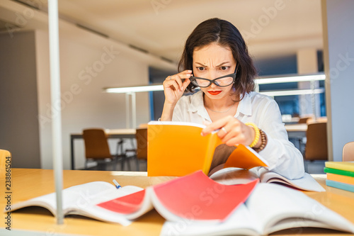 Surprised Woman reading Book in library