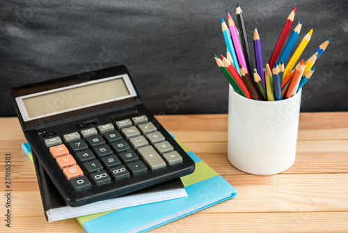 School supplies on black board background. Color pencils, calculator, rules and copybooks. Back to school concept. 1of September. photo