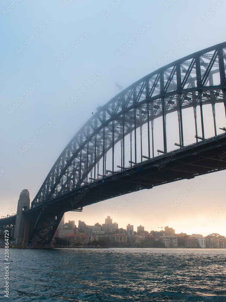 Sydney Harbour Bridge view under sunrise light and fog.