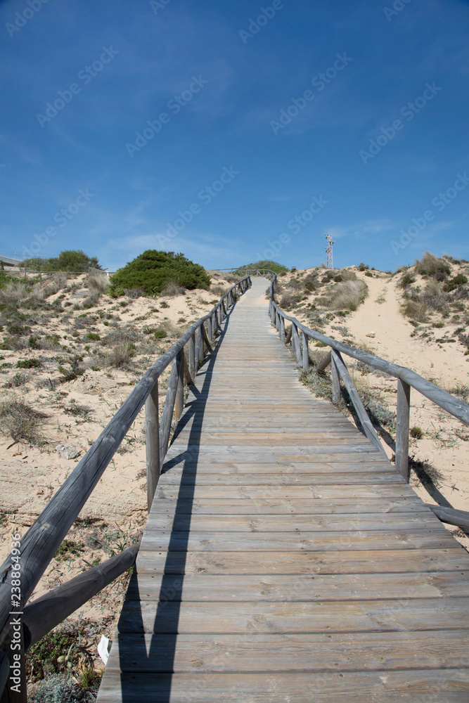 A wooden footbridge as a path through the dunes at a beach in Spain