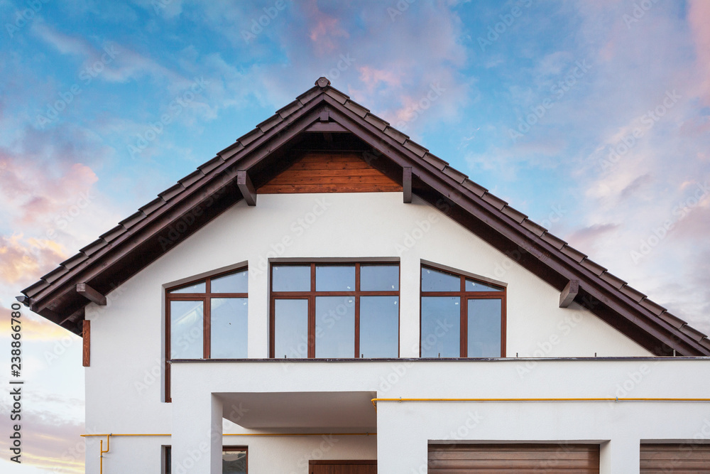 Photo of beautiful comfort and new house with brown roof large windows and white wall against calm blue sky Photo of beautiful comfort and new house with brown roof large windows and white wall against calm blue sky