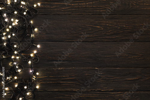 Christmas dark wooden background decorated with shining lights
