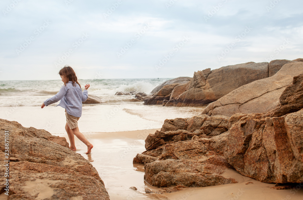 Five-year-old girl playing on the sandy beach of the sea