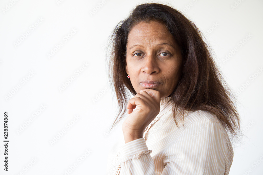 Pensive Latin woman turning face to camera and touching chin. Closeup of mid adult lady with copy space aside. Female portrait concept Pensive Latin woman turning face to camera and touching chin. Closeup of mid adult lady with copy space aside. Female portrait concept