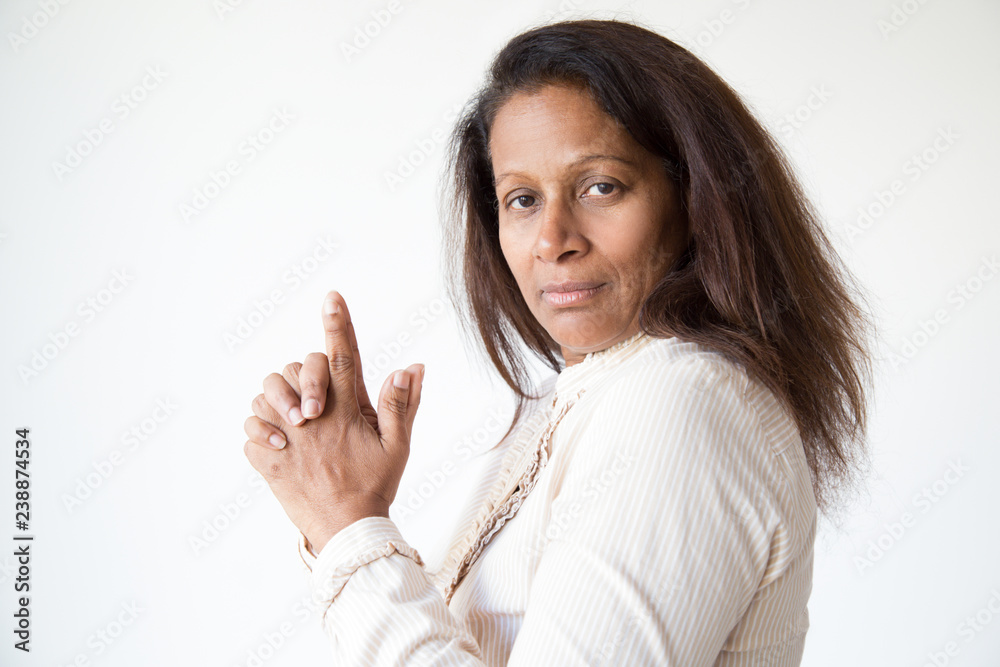 Serious mix raced woman fooling and acting at camera. Middle aged lady clasping hands and fingers like gun. Gun gesture concept Serious mix raced woman fooling and acting at camera. Middle aged lady clasping hands and fingers like gun. Gun gesture concept