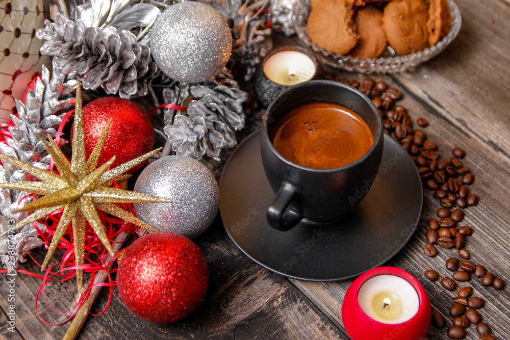 Black cup of coffee, cookies filled with chocolate, Christmas balls, candles and coffee beans. Close-up on the old rustic wooden table Black cup of coffee, cookies filled with chocolate, Christmas balls, candles and coffee beans. Close-up on the old rustic wooden table