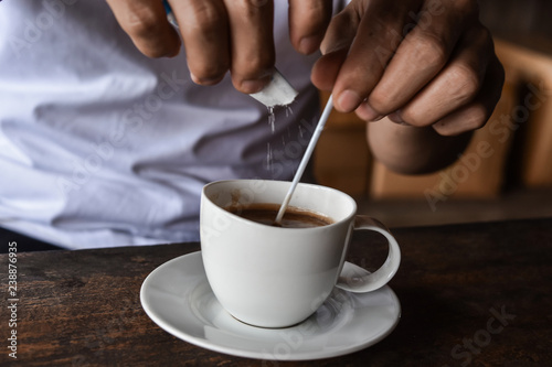 Closeup image of male hands pouring sugar Into the cup coffee. Preparation concept morning coffee.