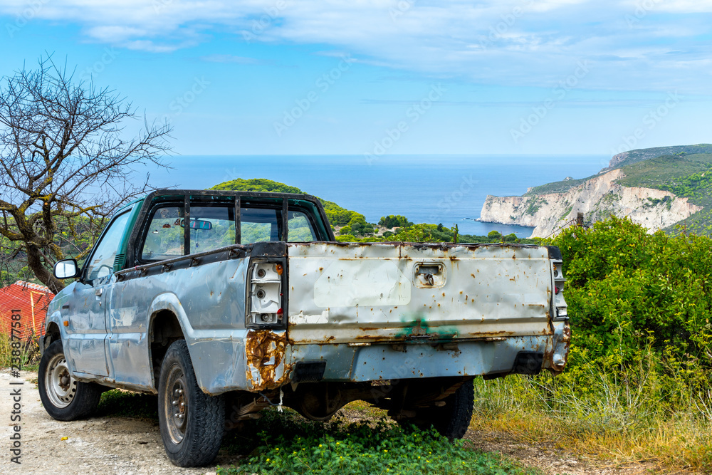 Rusty old car in front of beautiful ocean cliff landscape