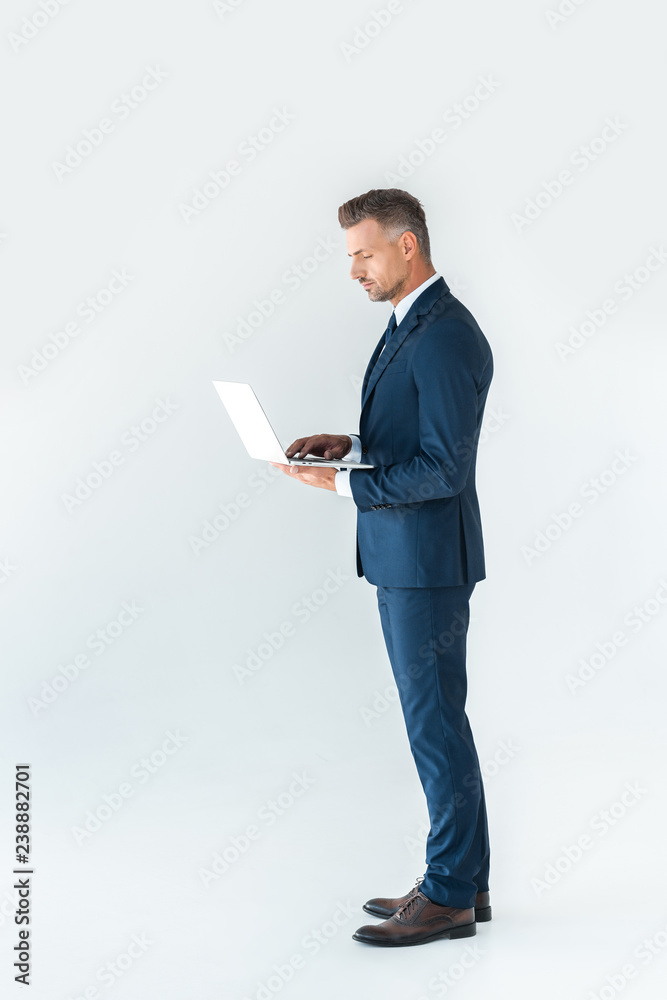 side view of handsome businessman in suit using laptop isolated on white side view of handsome businessman in suit using laptop isolated on white