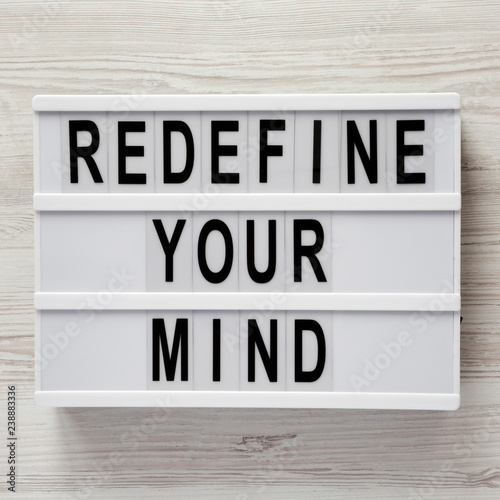 'Redefine your mind' words on modern board over white wooden background, top view. Overhead, flat lay, from above.
