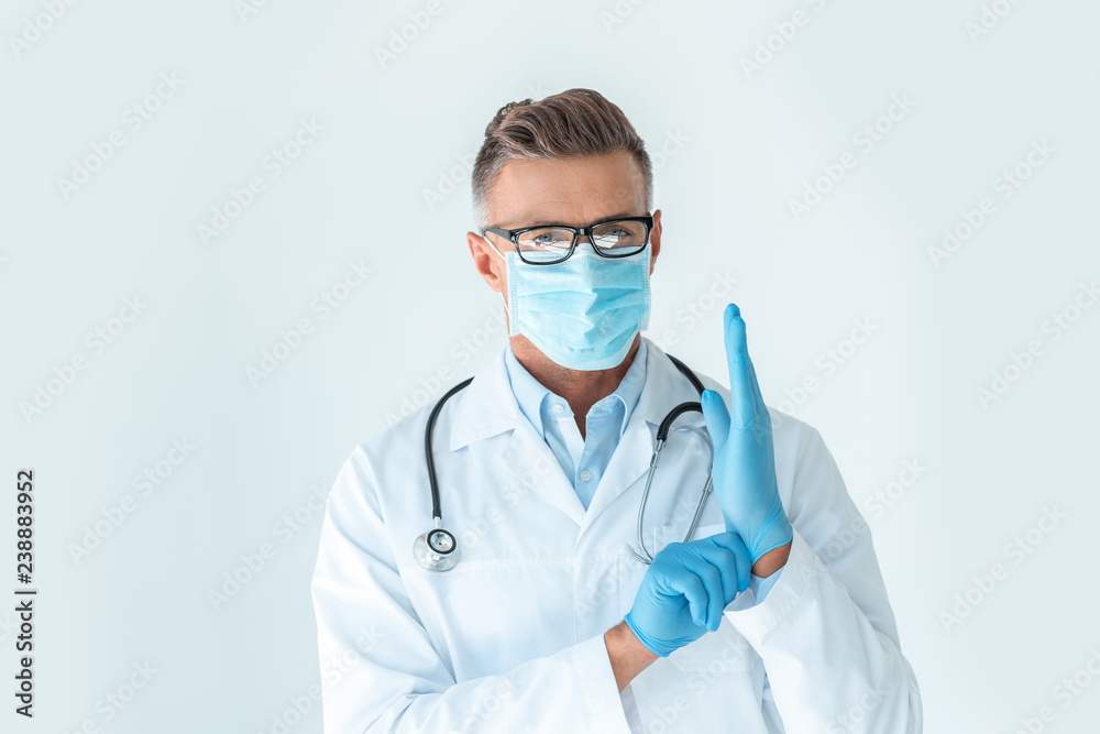 handsome doctor in medical mask wearing latex gloves and looking at camera isolated on white handsome doctor in medical mask wearing latex gloves and looking at camera isolated on white