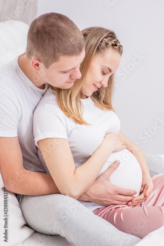 Happy family. Pregnant woman and her husband hugging on the bed