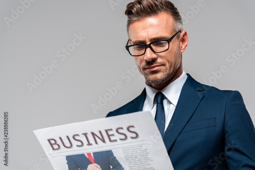 low angle view of handsome businessman reading newspaper isolated on white