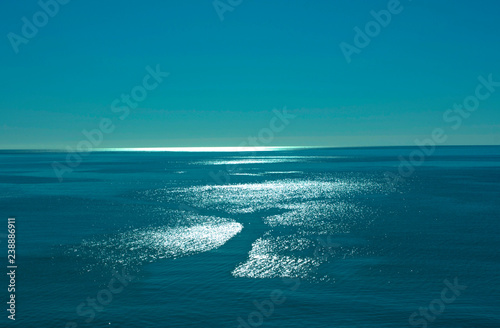 a fascinating seascape ultramarine sea surface and sun glare forming the silhouette of a girl on a sunny summer morning