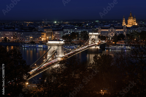 Szechenyi chain bridge budapest, lit up at night time, with St. Stephen's Basilica, in the background © parkerspics