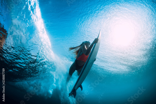 Attractive surfer woman dive underwater with under barrel wave.