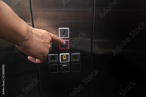 Men's hand with the press of control buttons interior elevator have braille panel for the disabled and empty space for text.