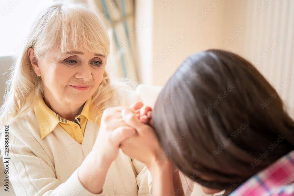 Daughter touches her foreheads with mother's hands intertwined with hers Daughter touches her foreheads with mother's hands intertwined with hers