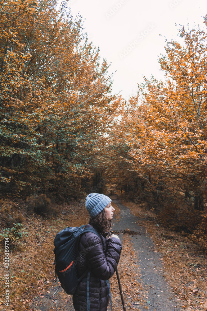 Woman with backpack walking in between trees Woman with backpack walking in between trees
