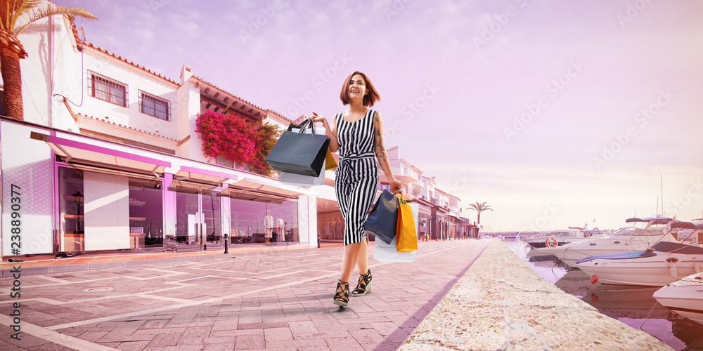 young beautiful lady walking after successful shopping. She smile and carry colour packages in their hands. kozy pink color tone