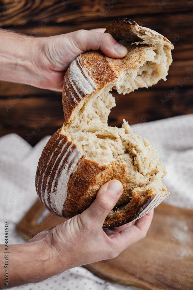 man breaks hands a loaf of fresh bread