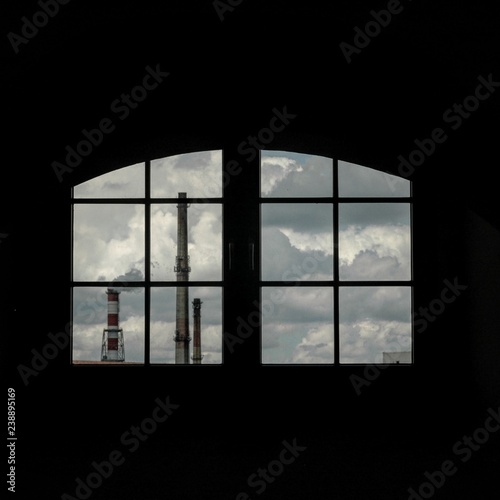 View from the window on the factory pipes, against the background of the cloudy sky