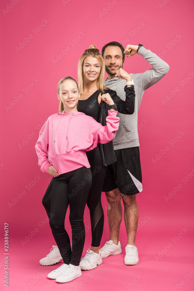 strong athletic family in sportswear showing muscular biceps, isolated on pink strong athletic family in sportswear showing muscular biceps, isolated on pink