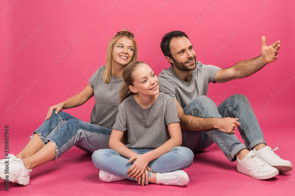 happy family with daughter sitting on pink while father showing something