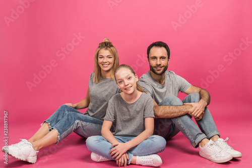 beautiful family with happy daughter sitting on pink