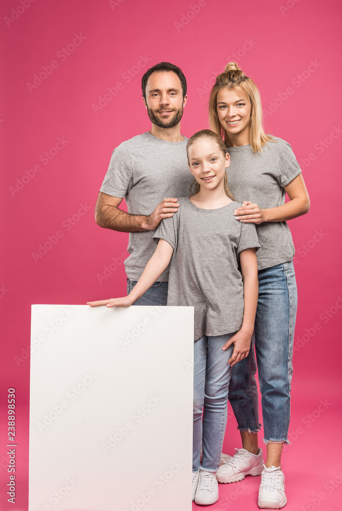 smiling parents and daughter posing with blank placard, isolated on pink smiling parents and daughter posing with blank placard, isolated on pink