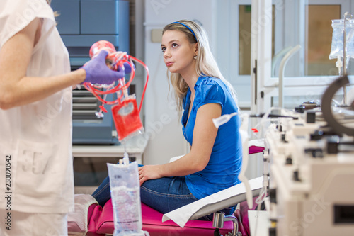 Young woman giving blood in a modern hospital - baing informed by the nurse of the transfusion unit photo