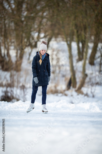 Young woman ice skating outdoors on a pond on a freezing winter day © lightpoet