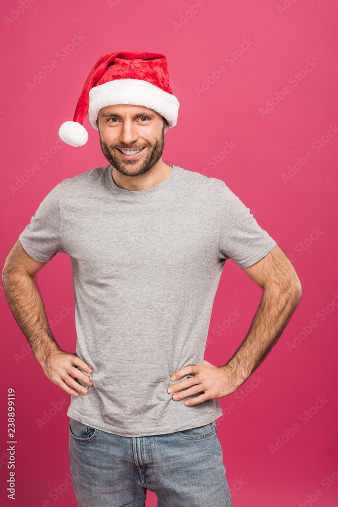 portrait of handsome smiling man in santa hat at christmastime, isolated on pink
