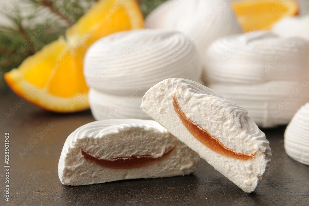 Sweet white marshmallows with orange filling and fresh oranges and a sprig of Christmas trees on a dark background Sweets. dessert. Sweet white marshmallows with orange filling and fresh oranges and a sprig of Christmas trees on a dark background Sweets. dessert.