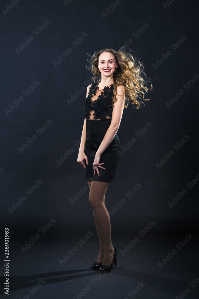 Portrait of a smiling young girl in a lace dress on a black background